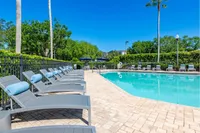 Inviting outdoor pool area with elegant lounge chairs and vibrant greenery, perfect for relaxation and leisure.