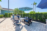 Charming outdoor patio with modern seating, vibrant umbrellas, and a built-in grill set against a lush garden backdrop.