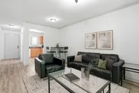 Inviting living room with stylish black leather furniture, modern decor, and open kitchen entry, perfect for cozy living.