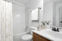 Bright and modern bathroom featuring a sleek white vanity, elegant faucet, and stylish patterned shower curtain.