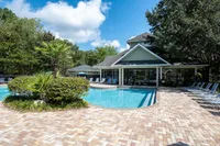 Inviting community pool with sun loungers set amidst lush greenery and modern clubhouse.