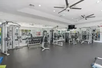 Modern fitness center featuring state-of-the-art weight training equipment, mirrored walls, and ample workout space.