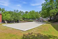 Inviting outdoor sand volleyball court surrounded by lush greenery and modern apartment amenities.