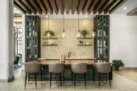 Elegant apartment bar with modern pendant lighting, chic seating, and stylish open shelving with decorative plants.