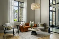 Chic living room with modern leather sofa, elegant armchairs, and stylish decor, accentuated by natural light through large windows.