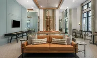 Contemporary entertainment room featuring a stylish leather sofa, elegant pool table, and modern decor with expansive windows and natural light.