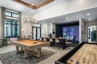 Luxurious entertainment room featuring a stylish billiard table, sleek gaming setup, and cozy seating area with modern decor.