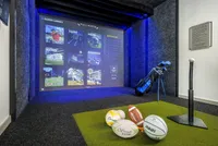 Luxurious sports simulator room featuring interactive game screen, golf equipment, and various sports balls, offering a premium entertainment experience.