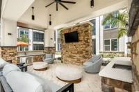 Luxurious outdoor lounge area with modern seating, stone accents, and a mounted TV, perfect for entertaining and relaxation.