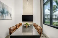 Elegant meeting room with plush leather chairs, a modern table, abstract wall art, and a large window providing a view of a serene outdoor landscape.