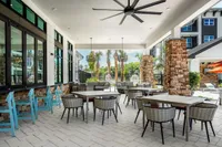 Inviting covered patio area with stone accents, stylish seating, and views of lush landscaping and palm trees.