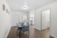 Bright and inviting dining area featuring a modern glass table, elegant light fixtures, and seamless access to a sleek kitchen and cozy living space.