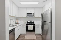 Bright and modern kitchen with sleek stainless steel appliances, pristine white cabinetry, and elegant countertops.