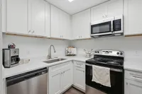 Modern kitchen with sleek white cabinetry, stainless steel appliances, and elegant quartz countertops.
