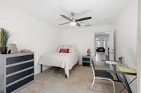 Charming bedroom with cozy decor, featuring a comfortable bed, modern ceiling fan, and sleek workspace. Ideal for relaxation and productivity.