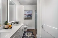 Elegant bathroom featuring a sleek vanity with twin sinks, modern fixtures, and decorative artwork for a sophisticated touch.