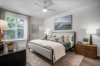 Elegant bedroom with modern decor, featuring a plush bed, stylish artwork, and abundant natural light through large windows.