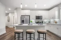 Elegant modern kitchen with sleek white cabinetry, stainless steel appliances, and a spacious island with seating, perfect for entertaining.