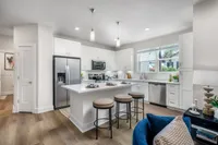 Modern kitchen with sleek white cabinetry, stainless steel appliances, and a central island with stylish bar stools, offering a bright and inviting space for cooking and entertaining.