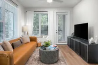 Chic modern living room with a stylish leather sofa, sleek coffee table, and large TV console, illuminated by natural light through expansive windows.