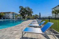 Inviting outdoor pool area with modern lounge chairs and lush greenery, perfect for relaxation and leisure.