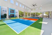Bright and modern covered sports court with vibrant blue and green surfaces, large fan, and open design for optimal recreation.