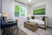 Bright and modern home office with a chic daybed, vibrant green artwork, and large window offering serene garden views.
