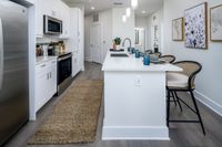 Modern kitchen with sleek white cabinets, stainless steel appliances, and an inviting breakfast bar with stylish seating.
