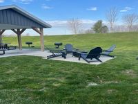 Relax and unwind at our outdoor fireside lounge. Charming outdoor area featuring Adirondack chairs, picnic tables, and grills under a picturesque sky, perfect for entertaining and relaxation.
