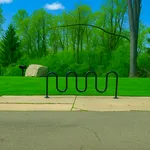 Bike-friendly living made easy with secure, on-site bike racks—designed for convenience, safety, and an active lifestyle just steps from your front door. Scenic park setting with a modern bike rack, lush green lawns, and dense forest backdrop under a vibrant blue sky.
