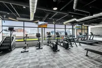 Modern fitness center with state-of-the-art equipment, expansive windows, and urban skyline views.