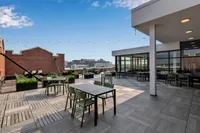Chic rooftop terrace with modern seating, lush greenery, and stunning city views, perfect for relaxation and social gatherings.