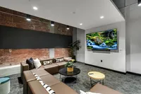 Chic living room with a modern L-shaped sofa, exposed brick accents, and a large wall-mounted TV showcasing a serene nature scene.