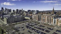 Vibrant urban skyline view with modern architecture and spacious parking area under a clear blue sky.