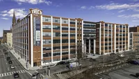 Impressive urban building with luxury apartments, featuring large windows and modern architecture, located on a bustling street with city views.