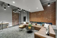 Modern industrial living space with exposed brick walls and stylish lighting fixtures, featuring a spacious sectional couch and contemporary decor.