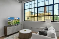 Bright modern living room with a cozy sofa, stylish coffee table, and a scenic view through large industrial-style windows.