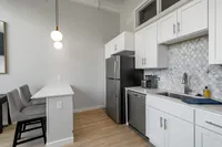 Modern kitchen with sleek white cabinetry, stainless steel appliances, and stylish pendant lighting, perfect for contemporary living.