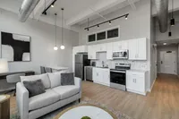 Modern open-plan apartment kitchen and living room featuring sleek white cabinetry, stainless steel appliances, and stylish contemporary decor.