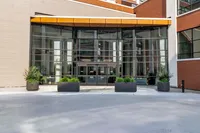 Modern apartment entrance with large glass windows and sleek design, featuring potted greenery for a welcoming atmosphere.