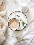 cup of coffee on a plate on top of linens