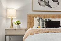 wicker bed headboard with nightstand and lamp. artwork frame on wall.