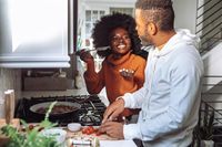 friends tasting their cooked meal at the stove