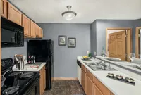 Modern kitchen with sleek black appliances, cozy wooden cabinetry, and elegant gray walls, perfect for culinary creativity.