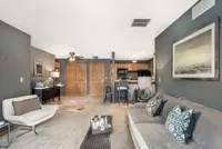 Modern open-concept living room with stylish decor, cozy seating, and a sleek kitchen with a breakfast bar.