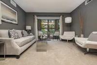 Elegant living room with plush gray sofa, modern chairs, and large windows offering scenic views, ideal for relaxation and entertainment.