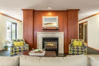 Elegant living room with a cozy fireplace, stylish armchairs, and natural light pouring in through windows. Perfect for relaxation and entertaining.