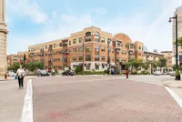 Charming urban apartment complex with modern architectural design, highlighted by red brickwork and large windows, situated on a bustling city corner.