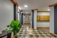 Modern apartment hallway with stylish tile flooring, elegant lighting, and vibrant green plants.
