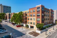 Contemporary apartment complex in urban setting featuring vibrant exterior, lush greenery, and ample parking.
